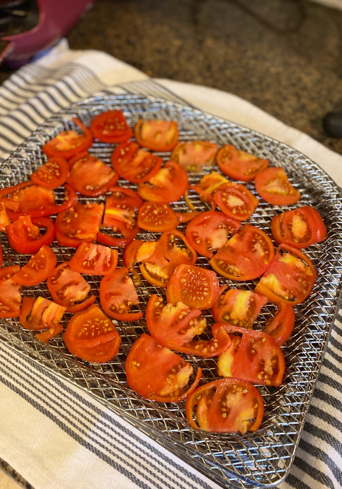 Sliced tomatoes on an air fryer tray, ready to be dehydrated.