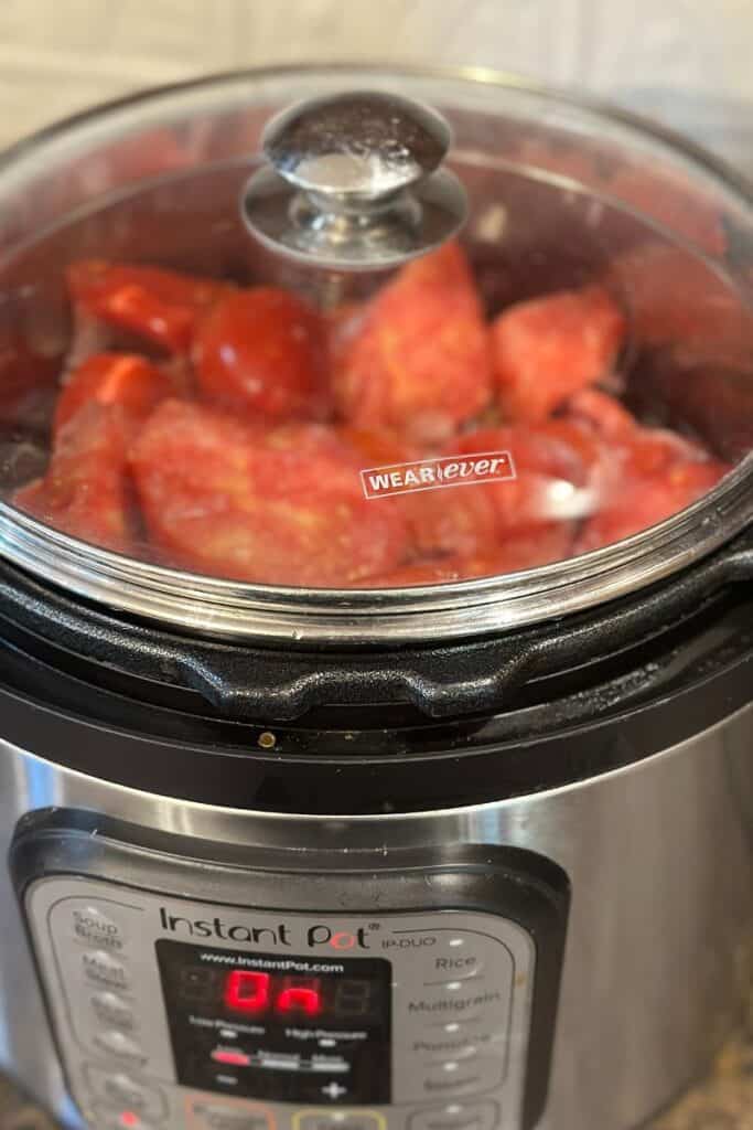 Frozen tomatoes in an InstantPot with a glass lid.