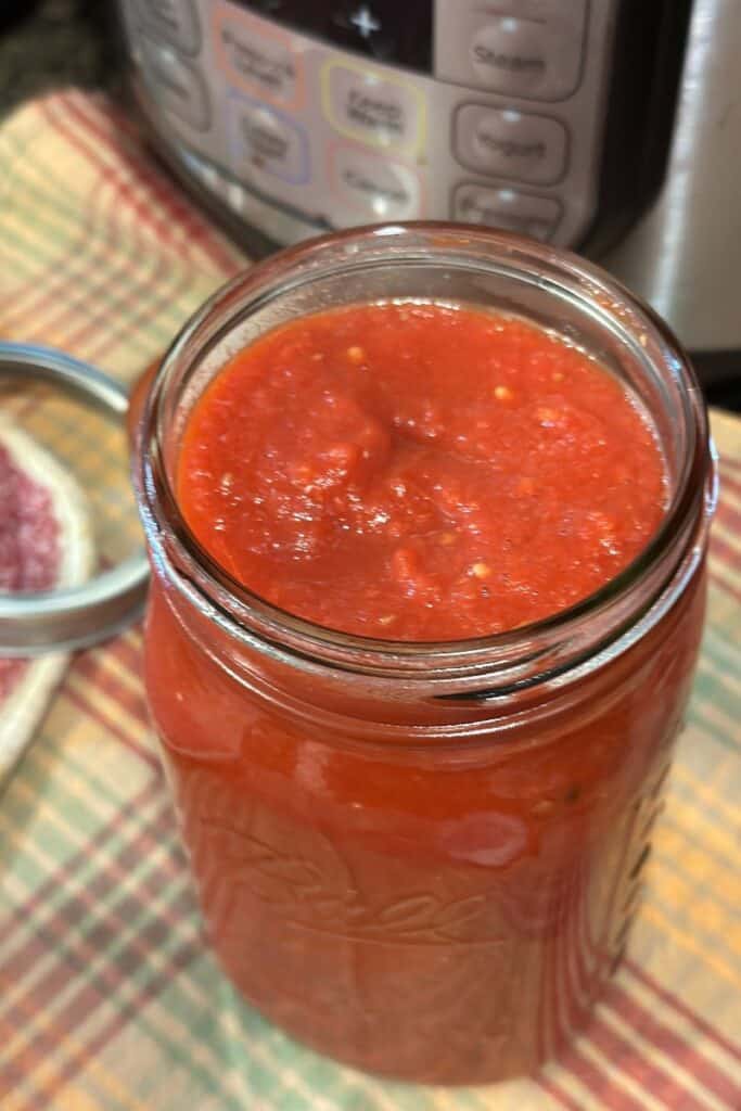 Finished tomato sauce ladled into a quart jar, ready to place lid and ring.