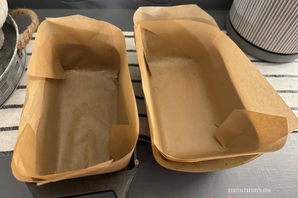 Two standard sized loaf pans lined with parchment paper.