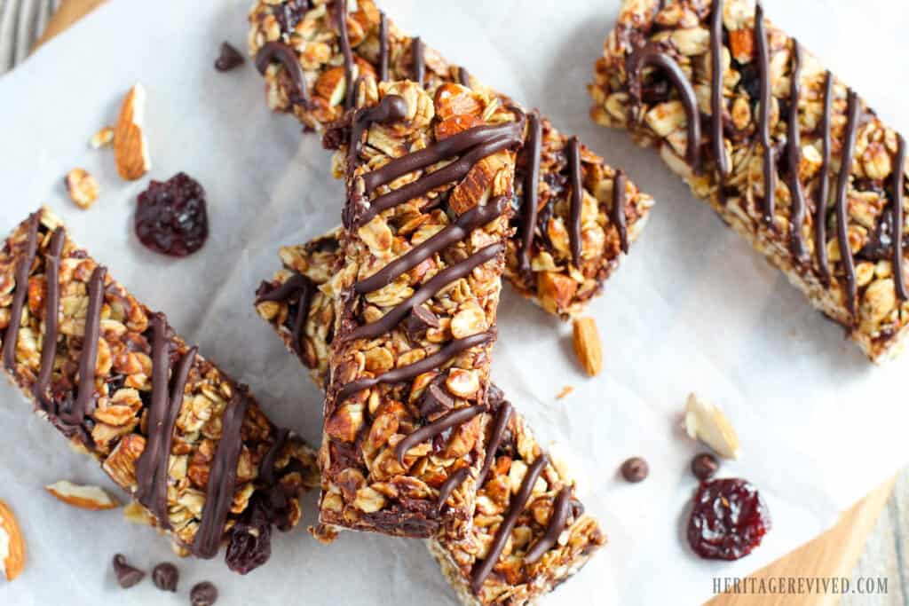 Maple syrup granola bars with cherries, almonds, and chocolate. Sliced and cooling on white parchment paper.
