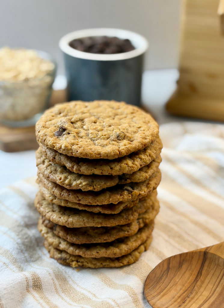 Fresh milled oatmeal chocolate chip cookies in a big stack on tea towel with flour mill in background.