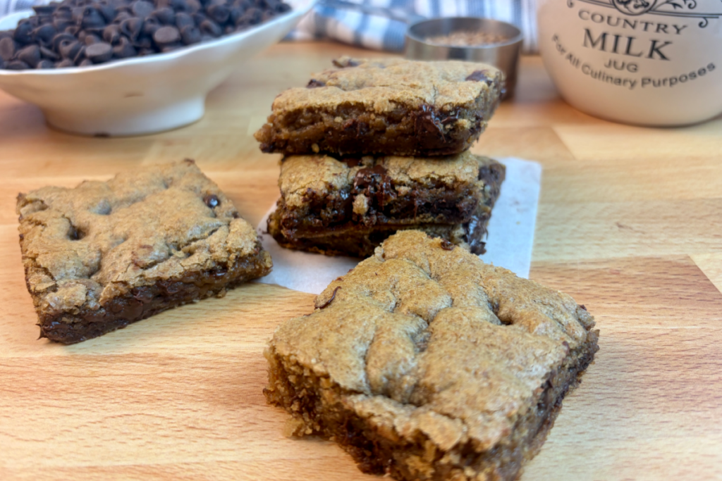 Gooey Cookie bars cut in squares with chocolate chips and grains in background