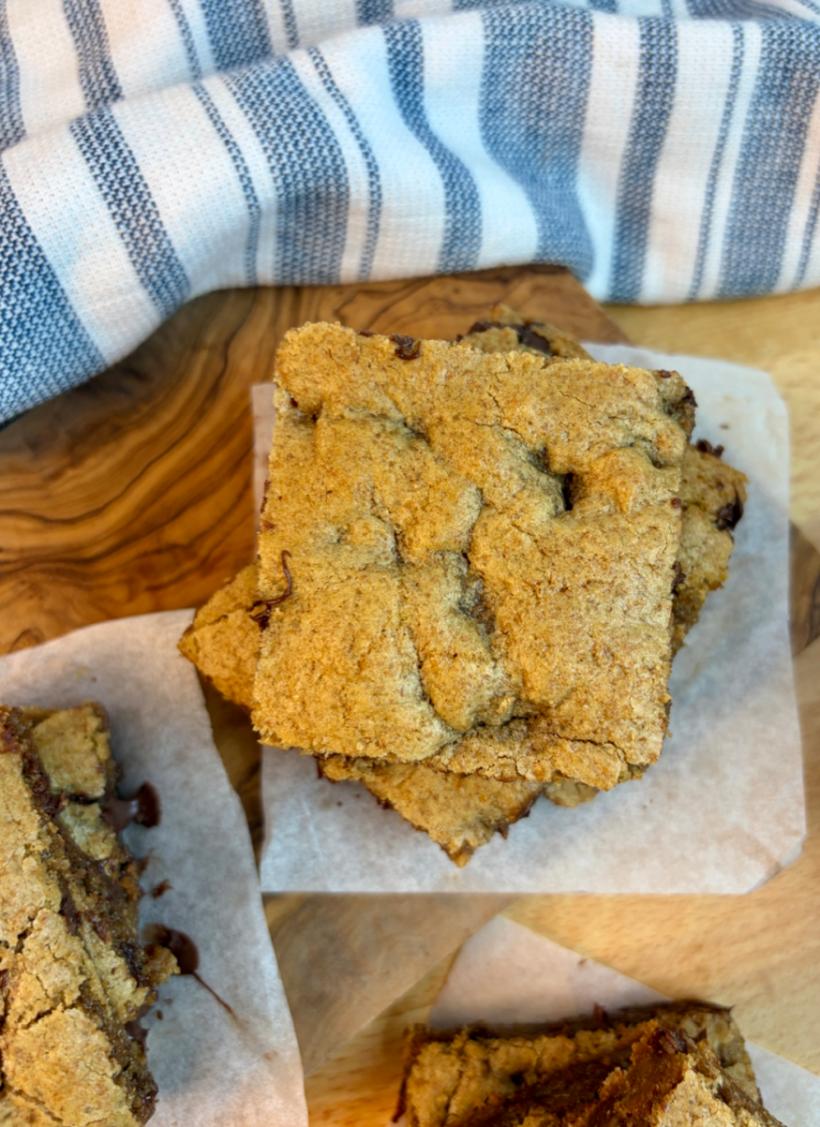Vertical image of cookie bars cut into squares on white parchment squares.