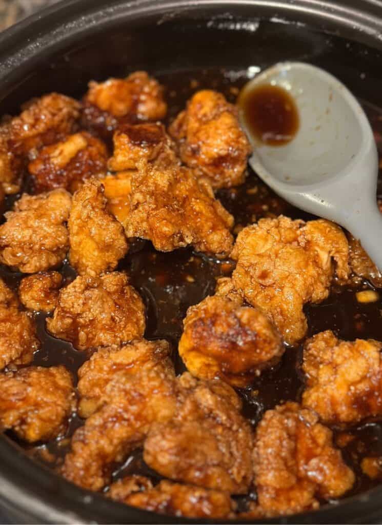 Fried chicken, tossed in sauce in saucepan.