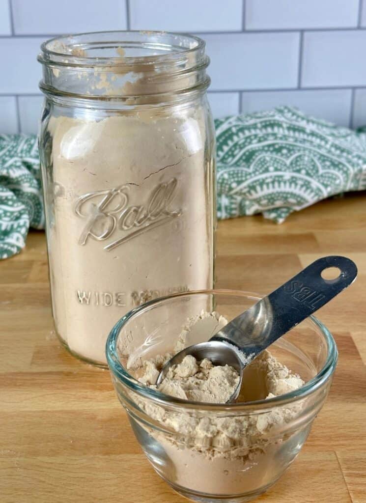 Pea protein powder in mason jar and in a small glass cup with measuring spoon.