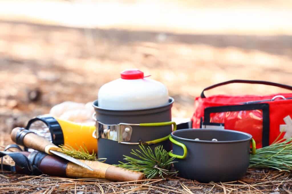 Various survival and emergency tools setting near a campsite.