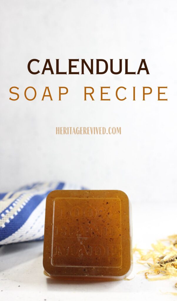 Vertical graphic with calendula soap bar setting on table with calendula flowers and tea towel in background