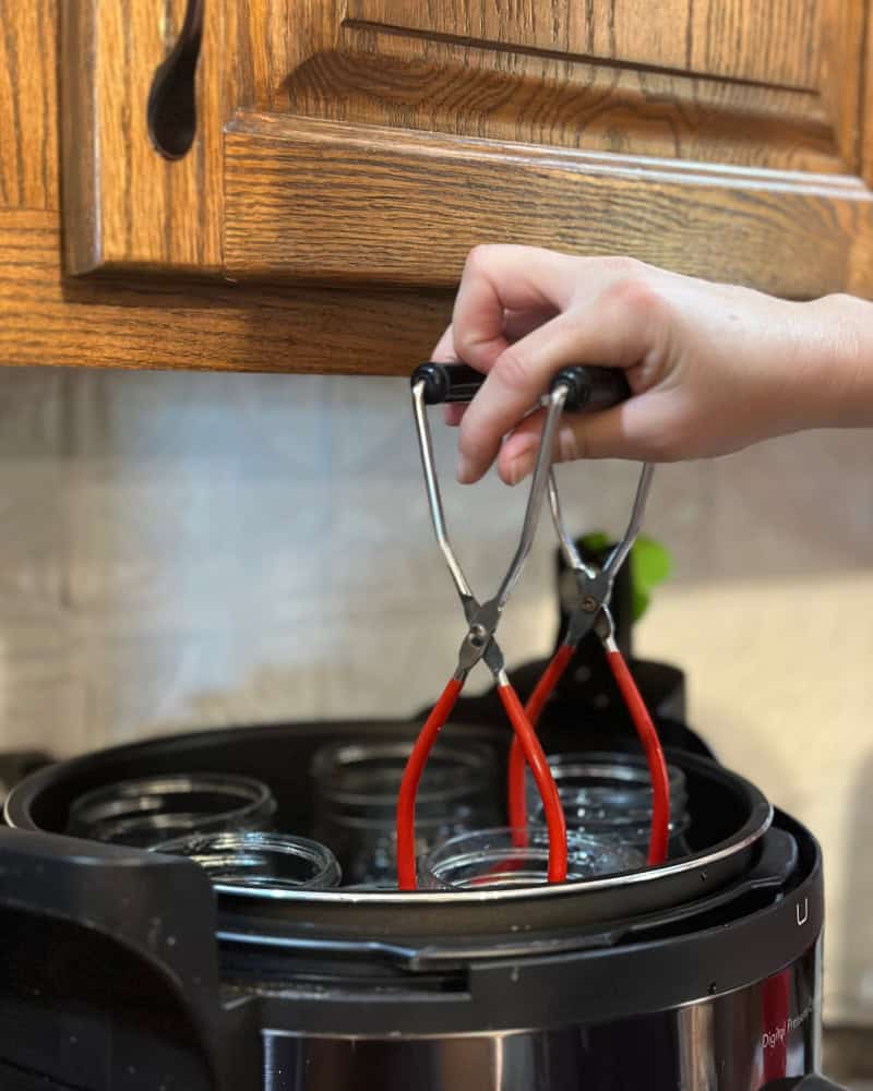 Lifting jars out of electric pressure canner with canning tongs.