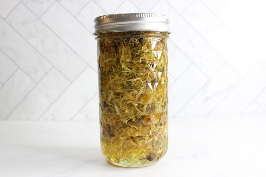 Calendula flowers and oil in a mason jar with lid.