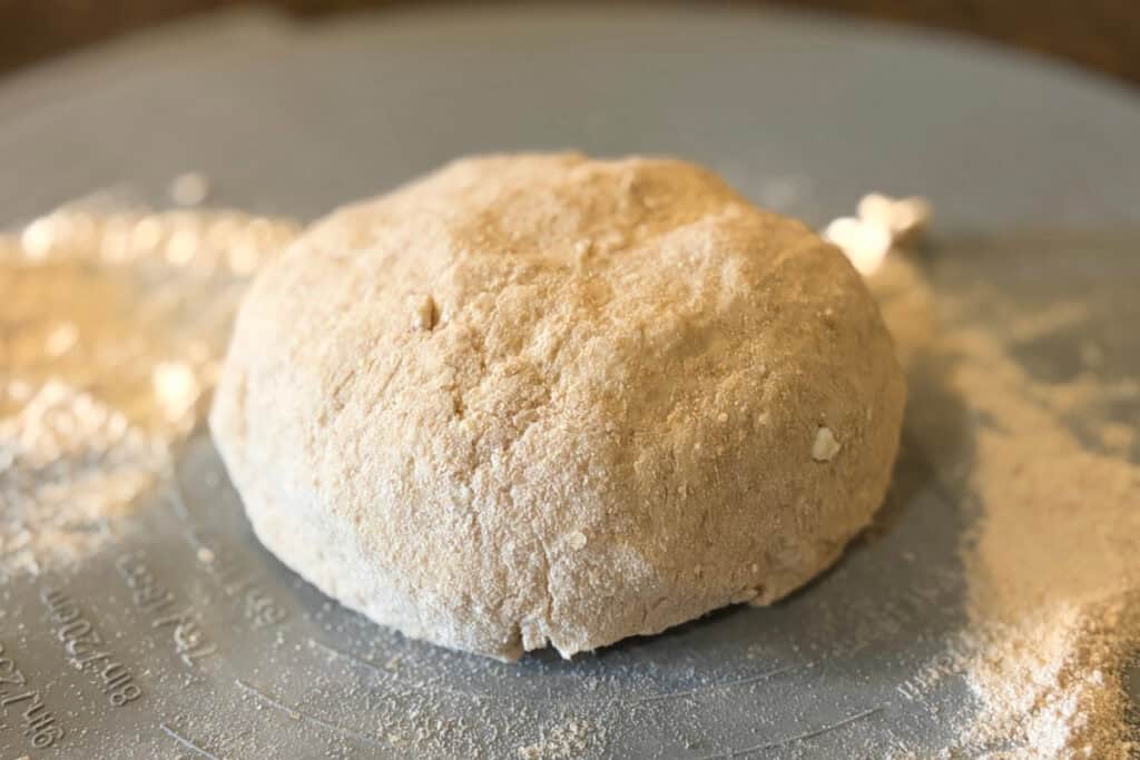 Round dough ball on a floured pastry mat.