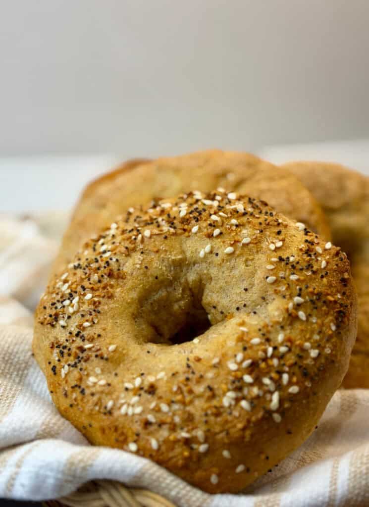 Vertical image of everything bagel on striped tea towel up close.