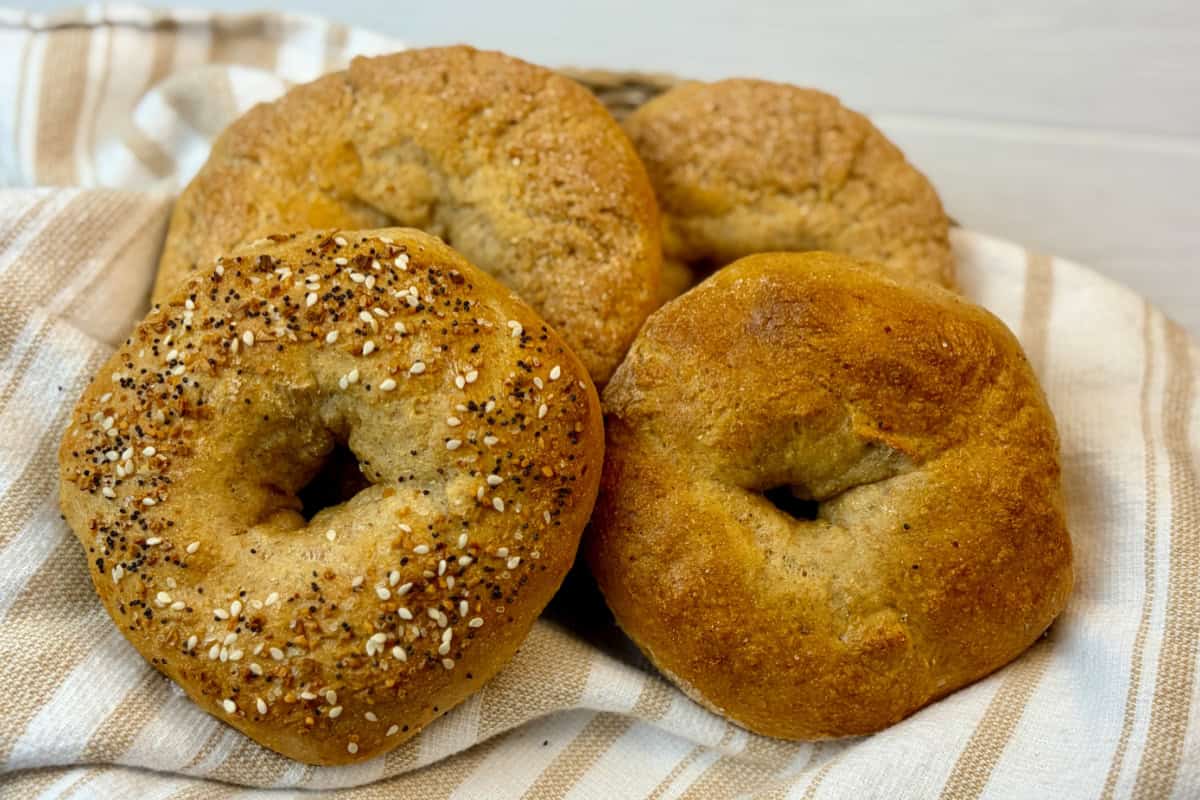 Four bagels on tea towel on white background.