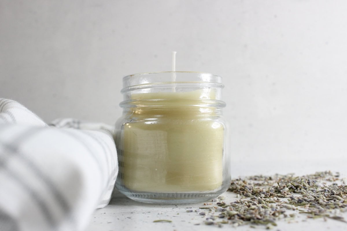 Lavender candle with dried lavender and striped tea towel.