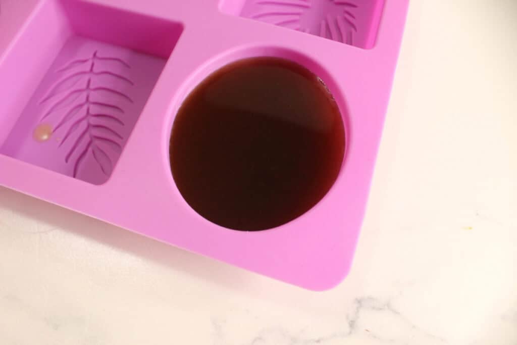 Pouring mixture for lotion bars into silicone mold.