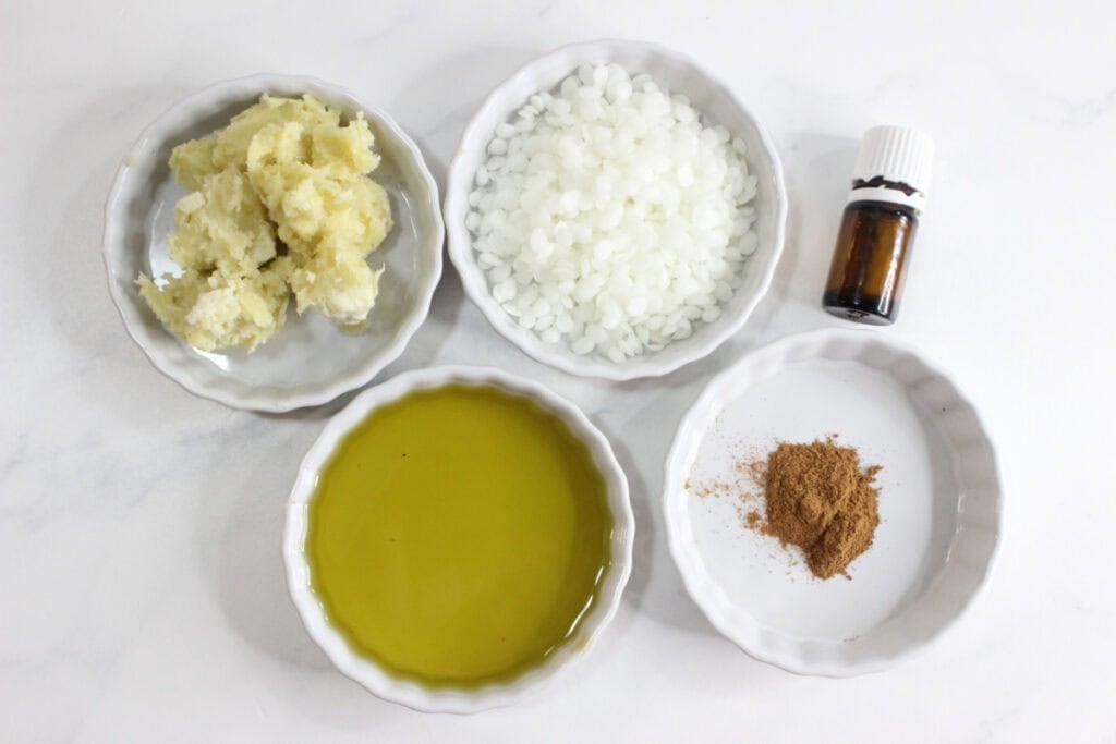 Supplies for lotion bars in ceramic dishes on white countertop.