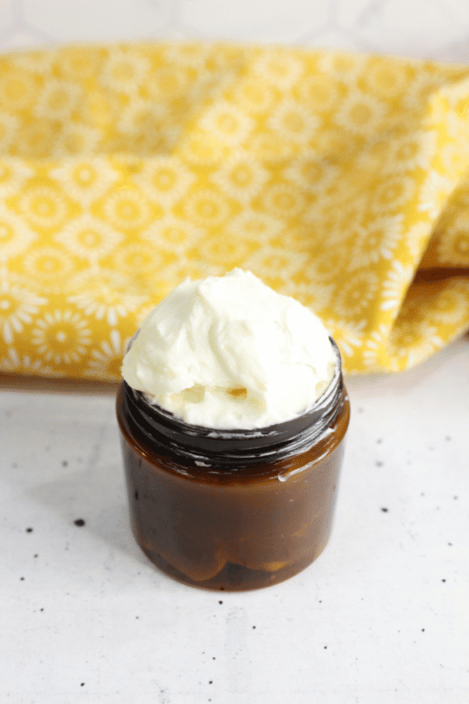 Amber jar of whipped tallow on a speckled white countertop.