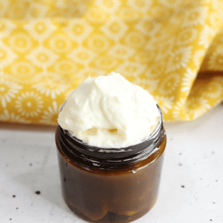 Small amber jar with whipped tallow and yellow textile in background.
