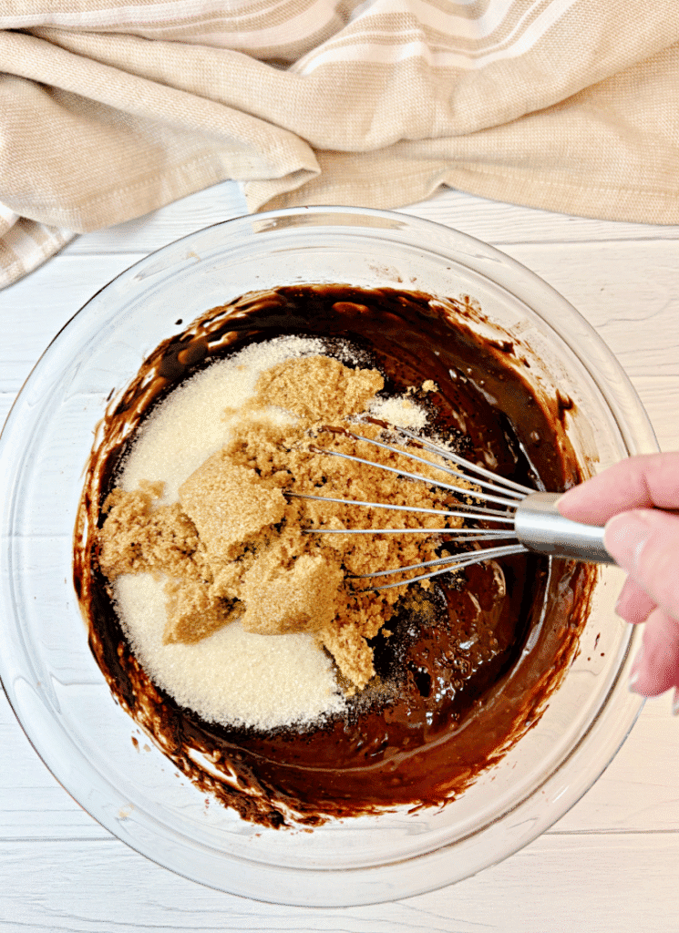 Mixing sugars and eggs into chocolate mixture.