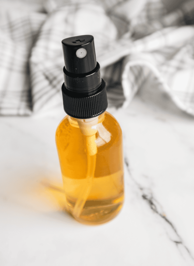 Small bottle of homemade tick spray on white countertop.